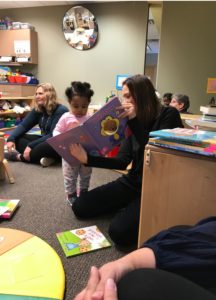 Amanda sitting down while reading to a child - Brew City Marketing