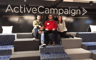 Connor, Nick and Amanda sitting in front of Active Campaign Sign