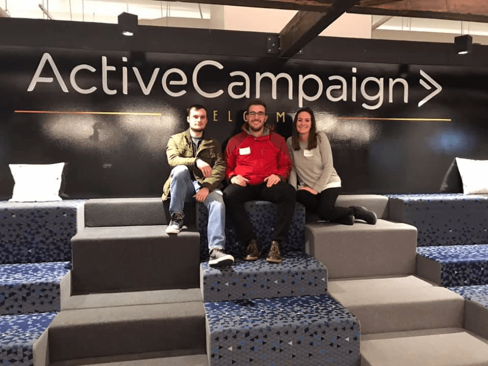Connor, Nick and Amanda sitting in front of Active Campaign Sign